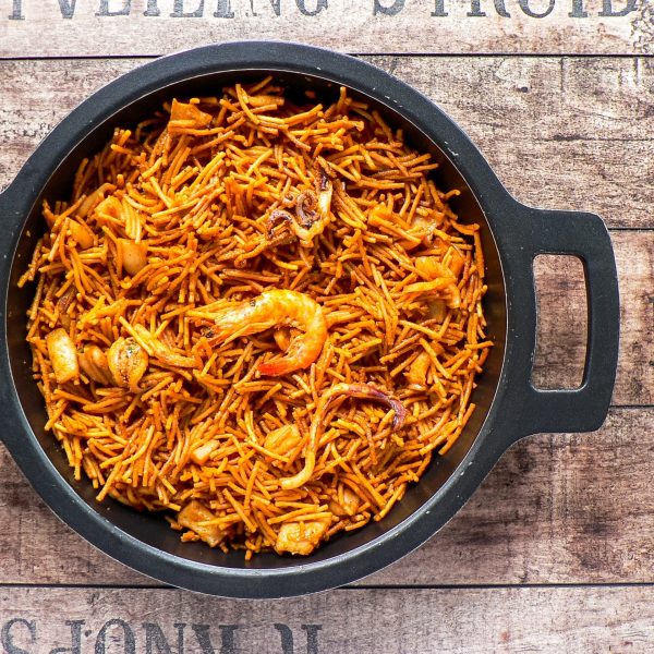 A top view of noodle paella a typical Catalan dish made with noodles and seafood with garlic sauce and oil in a black pot
